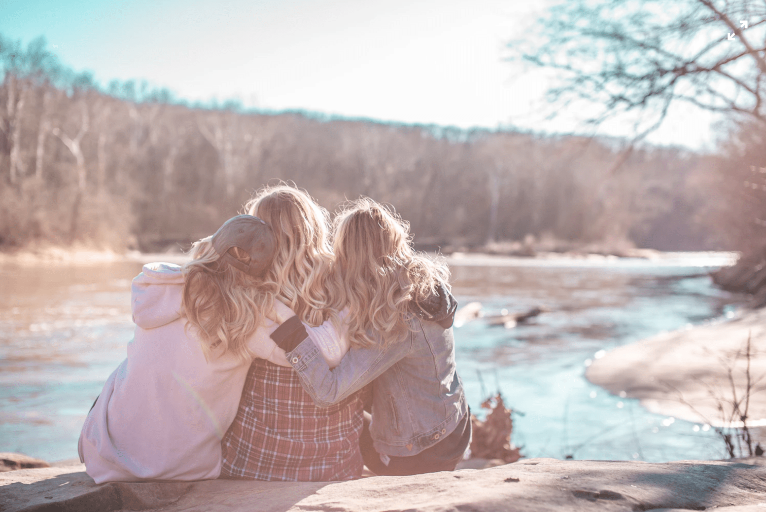 Three friends sitting on a rock by a river. Three friends sitting on a rock by a river.